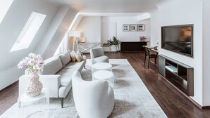 Un salon moderne avec un canapé, des fauteuils, une table basse et un téléviseur.