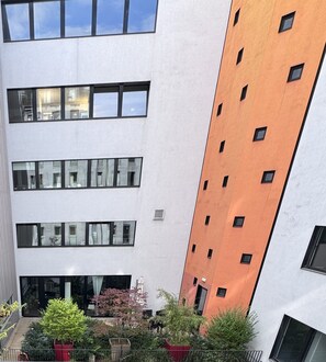A multi-story building with large windows and a courtyard with potted plants. - Hotel Q (Berlin)