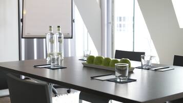 A conference room with a long table, two water bottles, a bowl of green apples, and glasses.