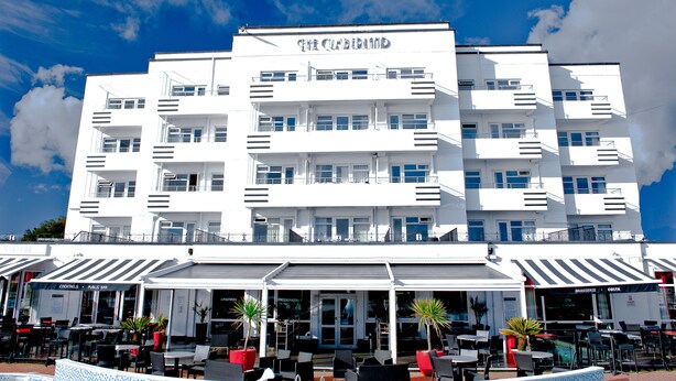 Ein weißes Hotel mit mehreren Balkonen und einer Dachterrasse.