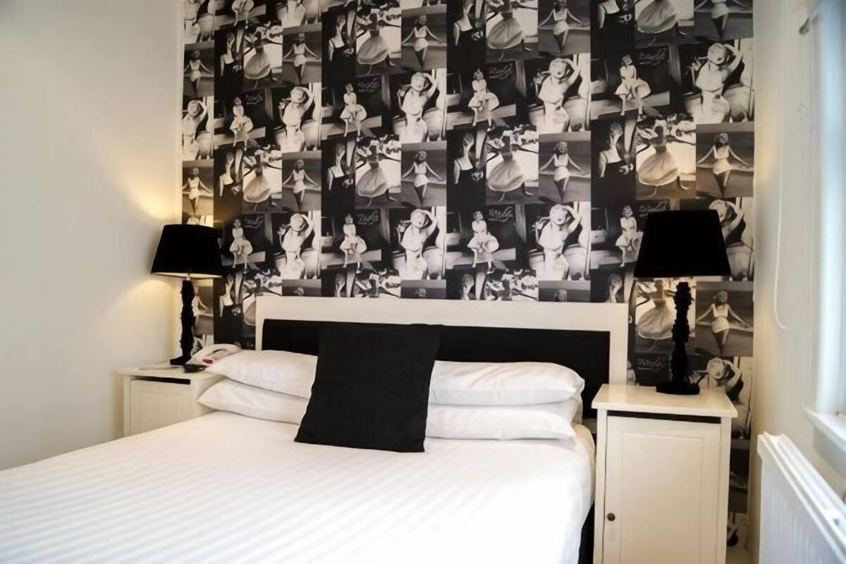 Camera da letto con un letto grande, due comodini, una testiera e carta da parati decorata.