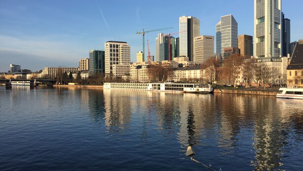 Un río con un bote y el horizonte de una ciudad al fondo.