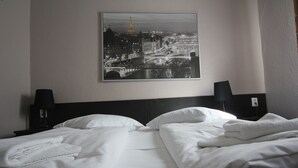 Habitación de hotel con dos camas, un espejo grande y vistas a un paisaje urbano con un puente y la Torre Eiffel.