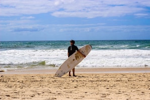 A person holding a surfboard on a beach with waves in the background. -  Trouville Bournemouth - OCEANA COLLECTION (Bournemouth)