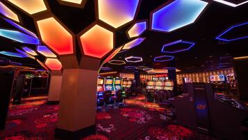 Experience entertainment in this vibrant space with gaming machines and seating areas, surrounded by a unique ceiling design and patterned carpet.