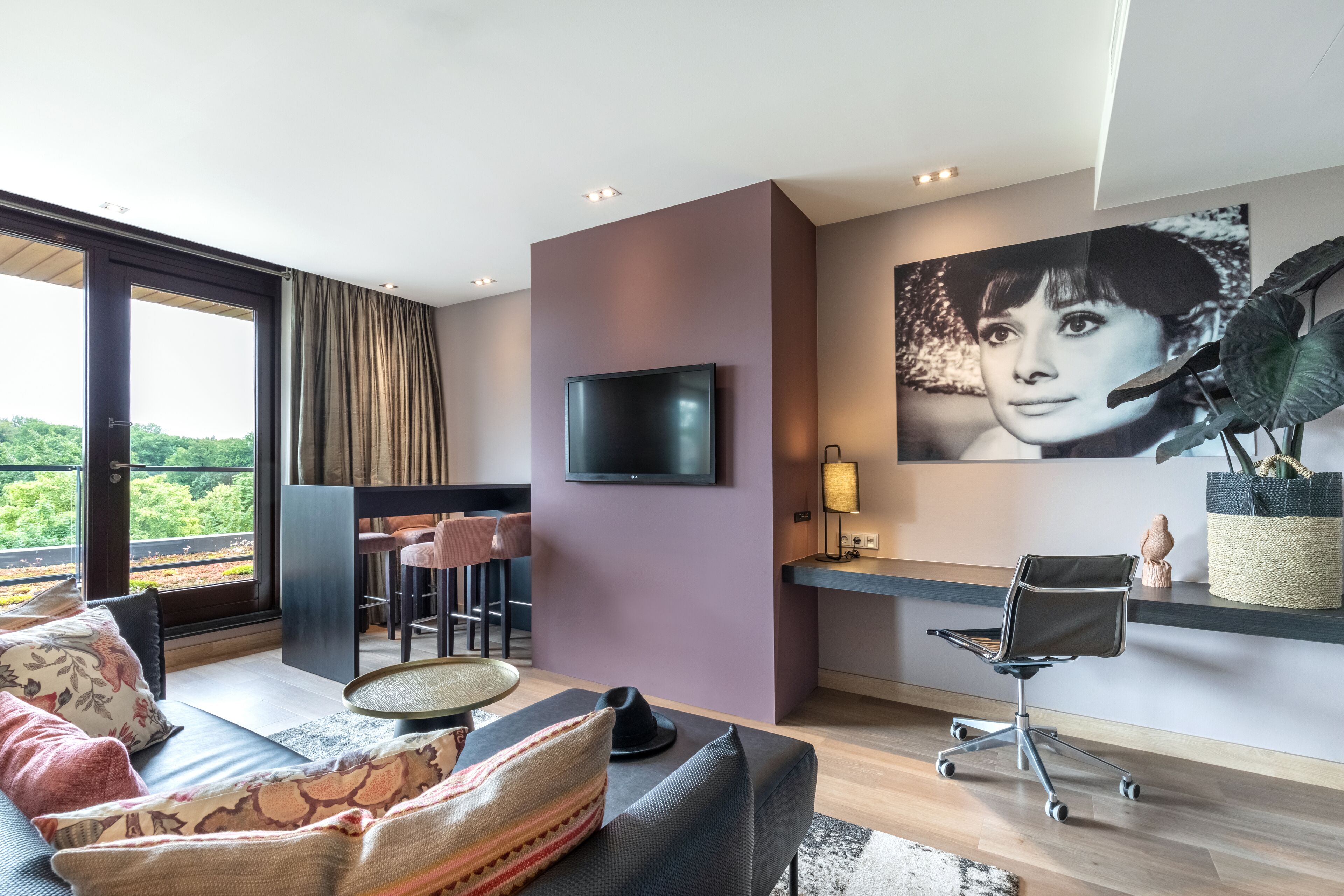 Una sala de estar moderna con un sofá, un comedor, un televisor y un escritorio con una computadora.