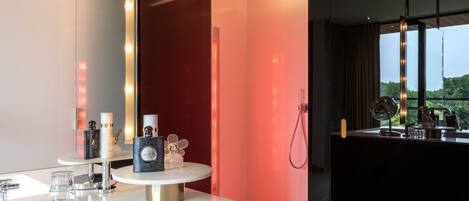 A modern bathroom with a white vanity, a round mirror, and a red accent wall.