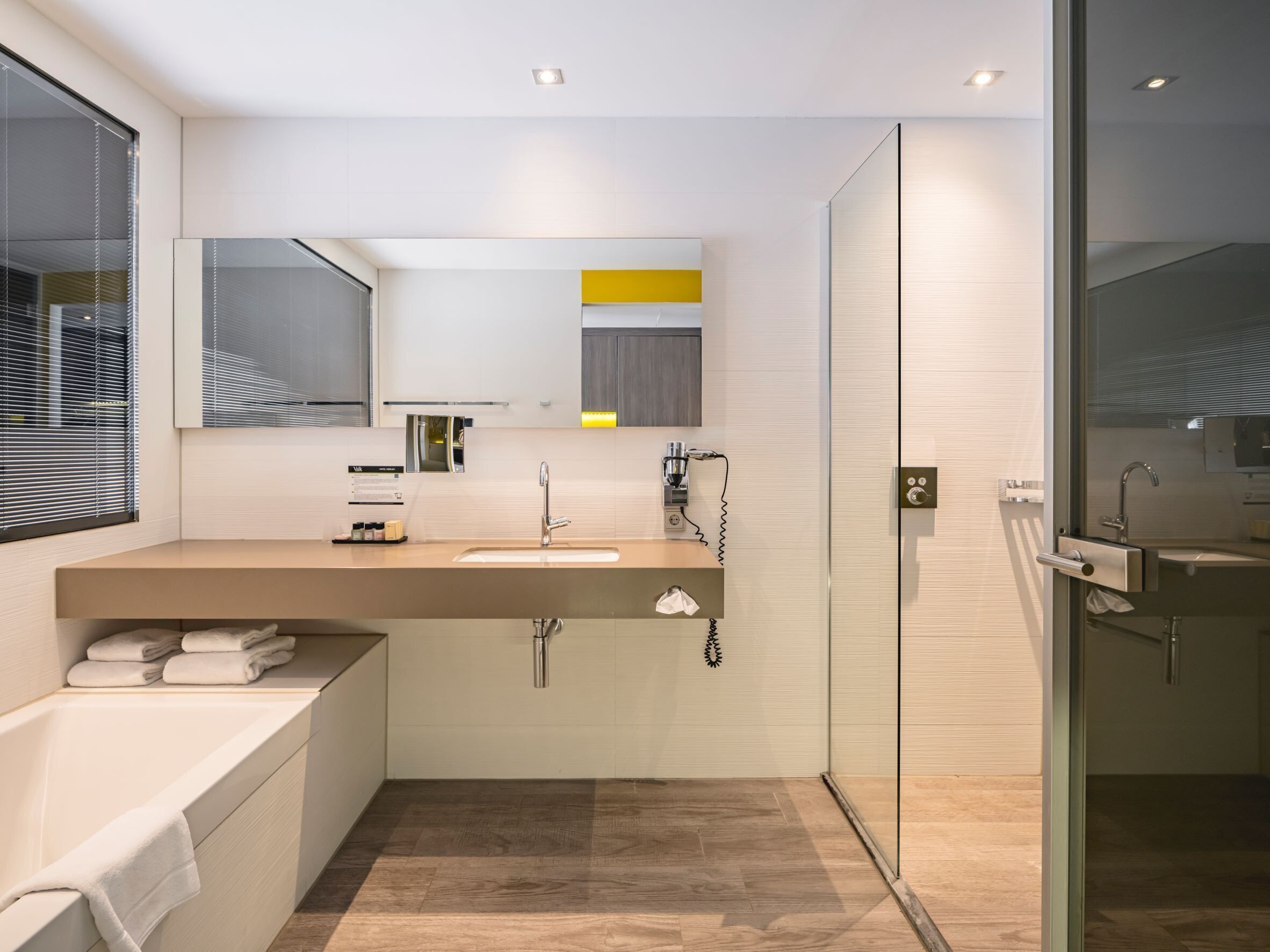 A modern bathroom with a bathtub, a sink with a mirror, and a glass shower enclosure.