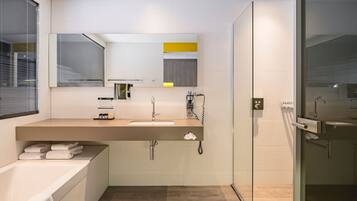 A modern bathroom with a bathtub, a sink with a mirror, and a glass shower enclosure.