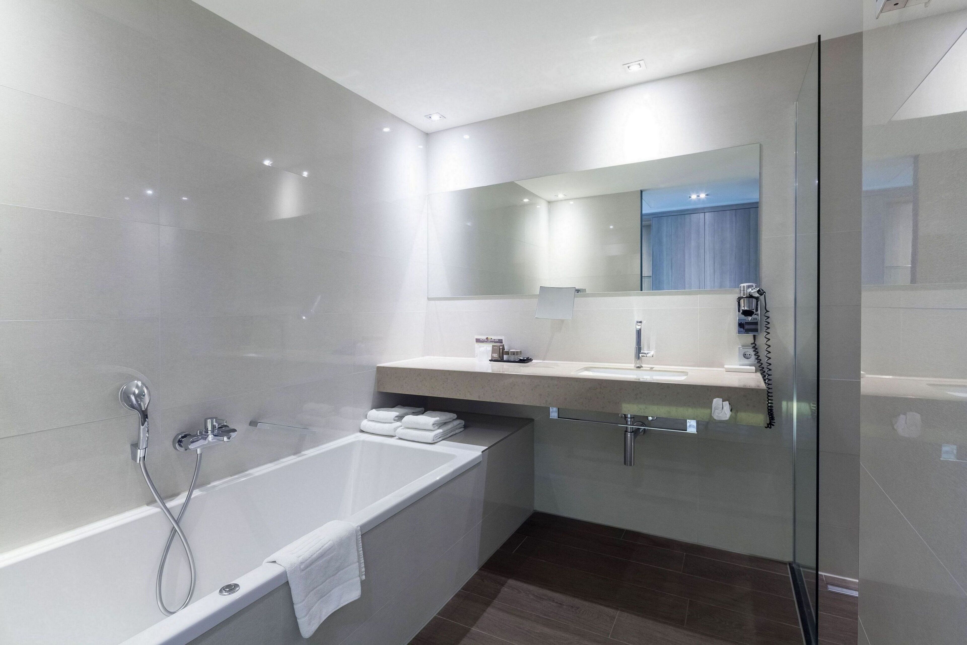 Een moderne badkamer met een bad, een wastafel met spiegel en een douchecabine van glas.