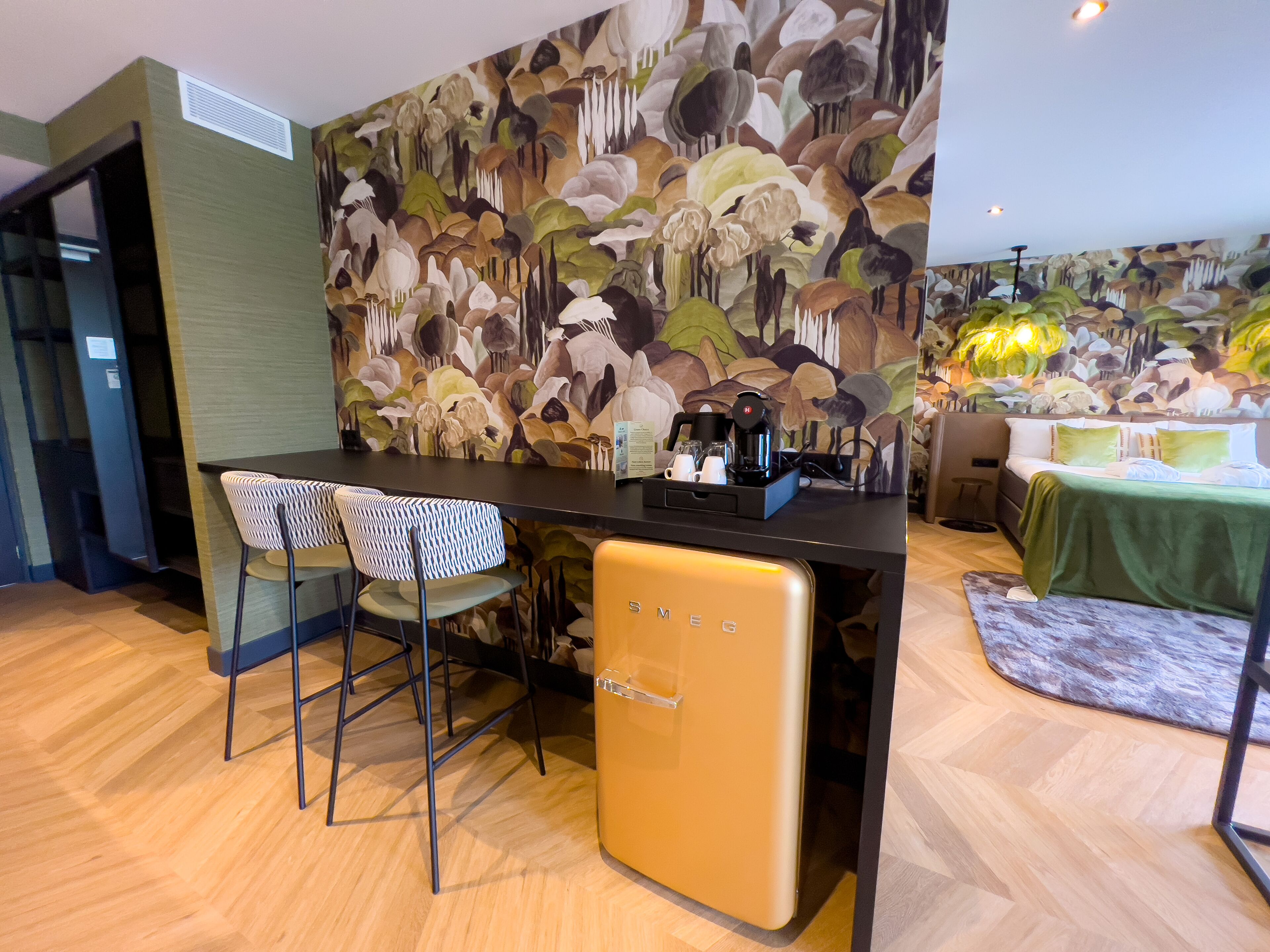 Una cocina moderna con una isla central, taburetes de bar y un refrigerador.