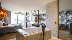 Un baño moderno con una bañera independiente, ducha con mampara de vidrio y piso de mármol.