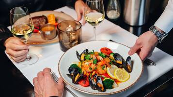 Une table à manger avec un plat de fruits de mer, des verres à vin et une bougie.