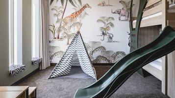 Una habitación con un tobogán, una cama con estampado de cebra, una tienda de campaña y un mural de animales.