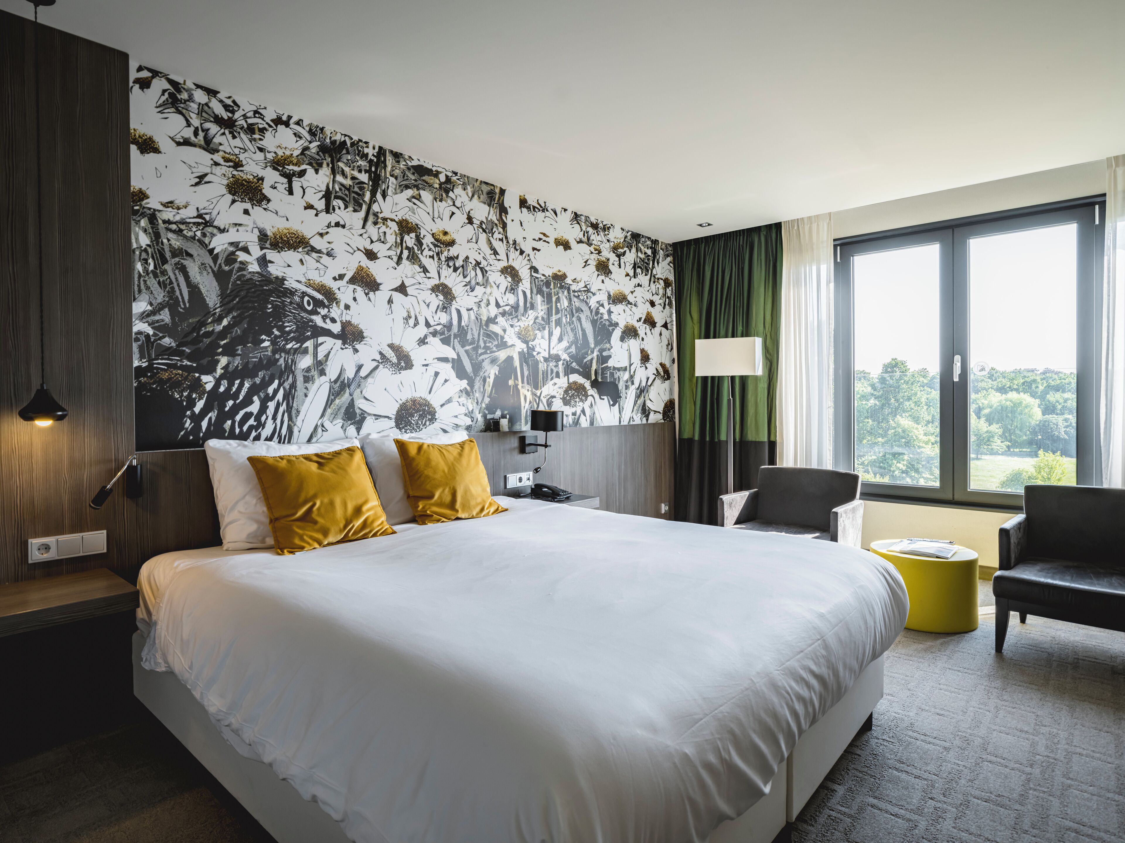 A hotel room with a large bed, a desk, a chair, and a view of the outdoors.