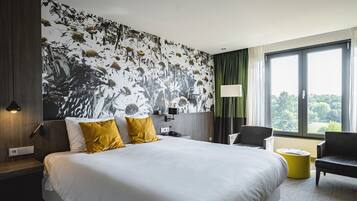 A hotel room with a large bed, a desk, a chair, and a view of the outdoors.