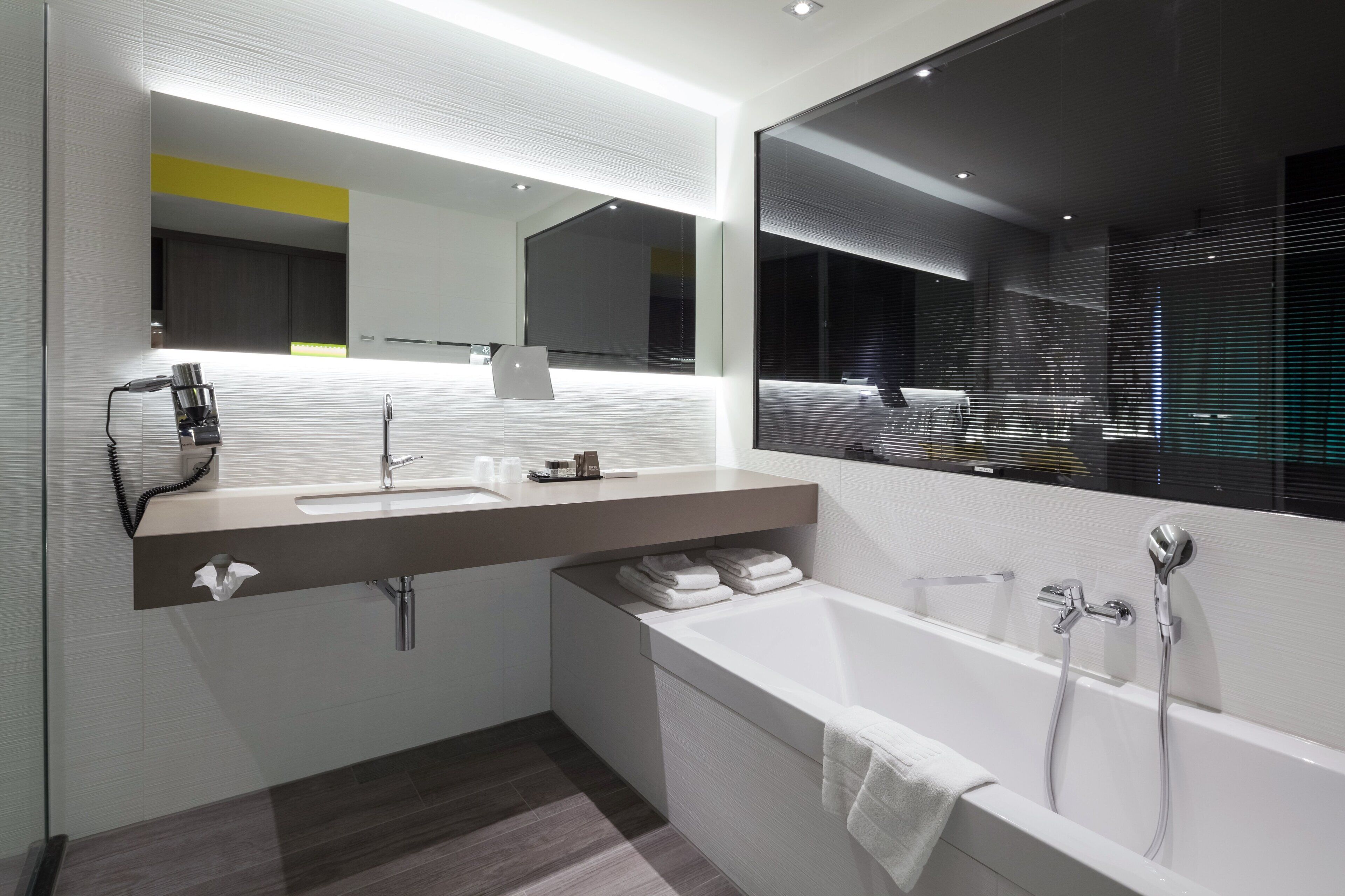 Une salle de bain moderne avec un grand miroir, un lavabo et une baignoire.