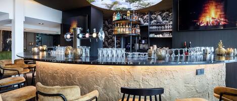 A bar area with a central round bar, multiple seating options, and a large screen displaying a fire scene.