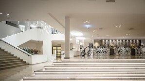 Un moderno vestíbulo de hotel con una escalera, un mostrador de recepción y una bicicleta estacionada cerca de la entrada.