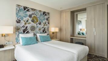 Een hotelkamer met een groot bed, twee bedlampen, een spiegel en een kledingkast.