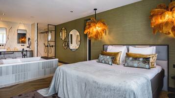 A modern bedroom with a large bed, a built-in bathtub, and a vanity with a mirror.