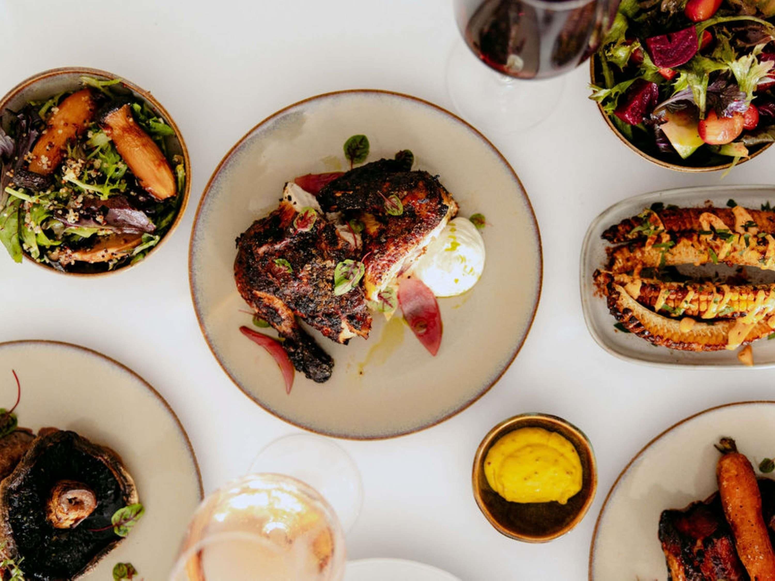A variety of dishes on a table, including grilled fish, vegetables, and a salad.
