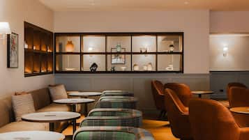 A modern interior with a sofa, multiple tables, and chairs arranged for dining or socializing.