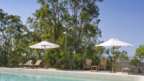 A clear swimming pool with lounge chairs and umbrellas, surrounded by trees. - Mercure Clear Mountain Lodge (Cashmere)