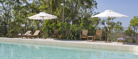 Una piscina al aire libre, sillones reclinables de piscina