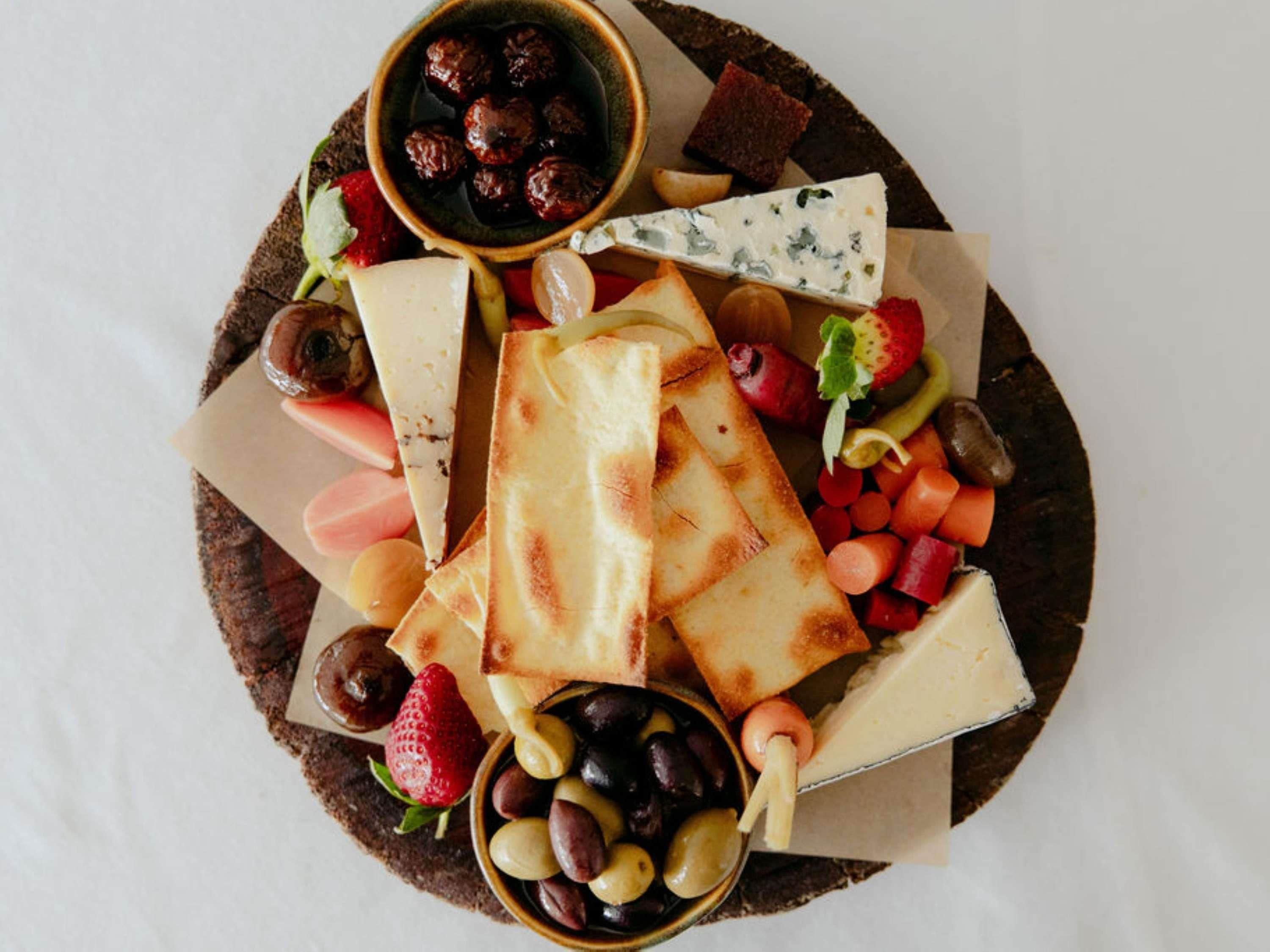 A charcuterie board with various cheeses, fruits, and olives.