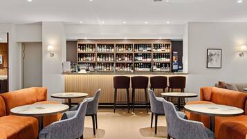 A bar area with multiple shelves of bottles, bar stools, and tables.