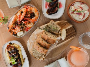 A variety of dishes including seafood, bread, and a drink, arranged on a wooden table. -  Peppers Clear Mountain (Cashmere)