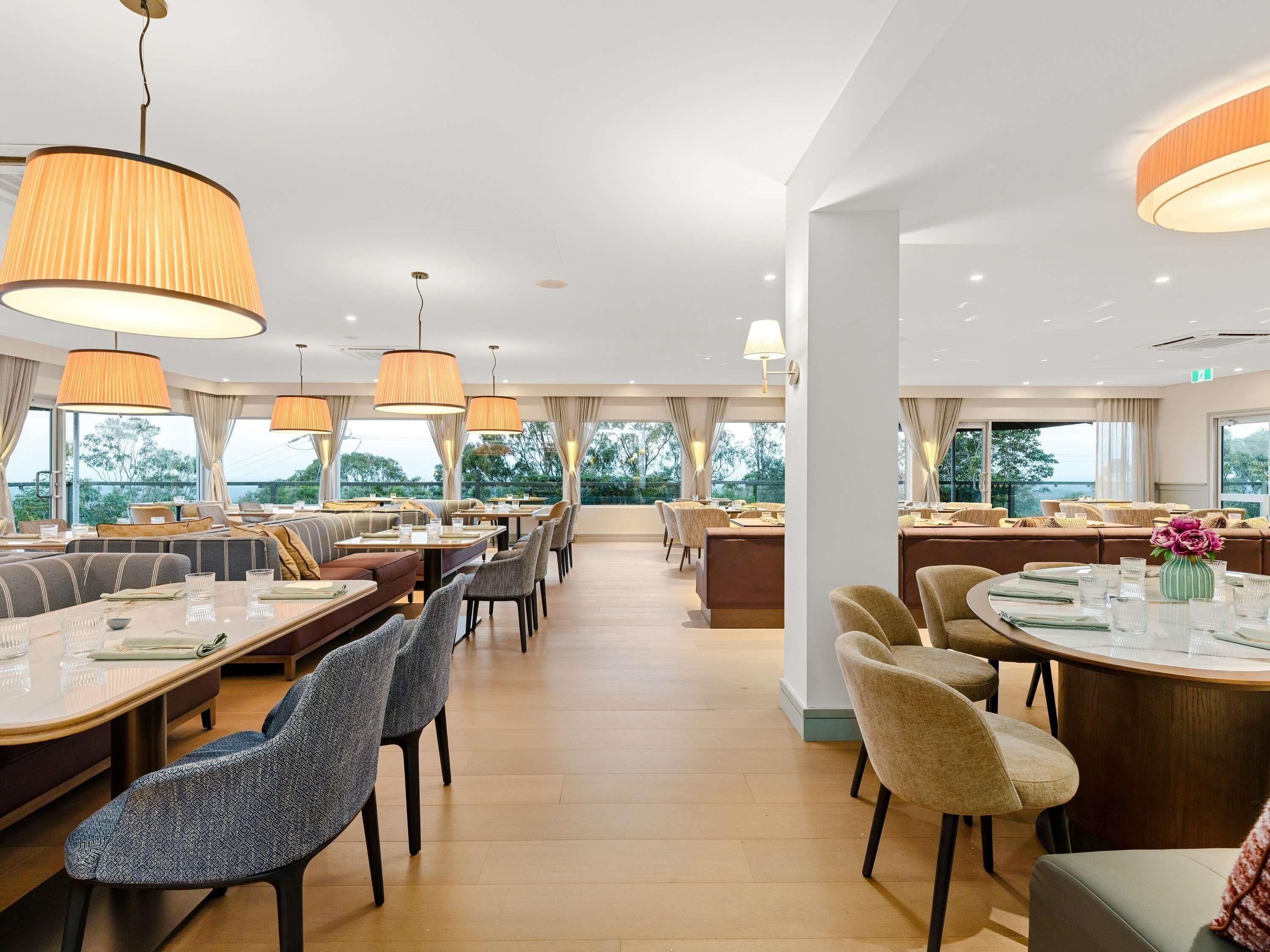Un comedor moderno con techos altos, ventanas amplias y vistas al exterior.