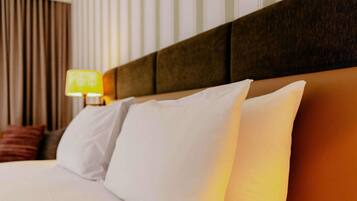 A hotel room with a neatly made bed, a headboard, and a lamp on a bedside table.