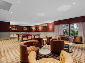 A room with a pool table, leather armchairs, a billiards table, and a view of greenery outside. - Peppers Clear Mountain (Cashmere)