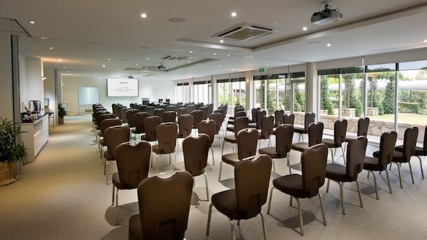 A conference room with rows of chairs, a projector screen, and a presentation area. -  Peppers Clear Mountain (Cashmere)