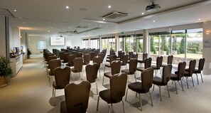 A conference room with rows of chairs, a projector screen, and a presentation area. - Mercure Clear Mountain Lodge (Cashmere)