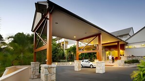 A modern hotel entrance with a covered driveway, stone pillars, and a car parked inside. - Mercure Clear Mountain Lodge (Cashmere)