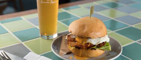 A meal with a burger and a glass of beer on a table with a checkered tablecloth.