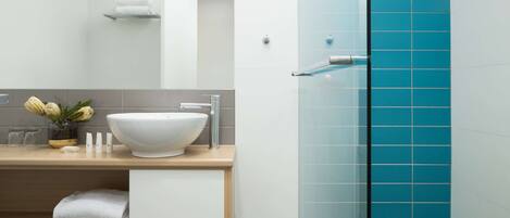 Un baño moderno con un lavamanos blanco, un espejo y una ducha con azulejos azules.