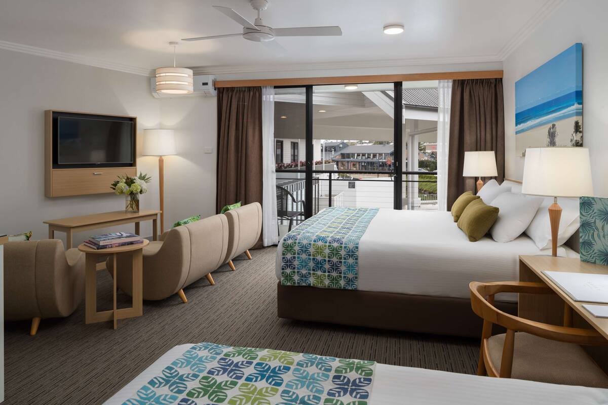 Une chambre d’hôtel avec un lit, un bureau, une télévision, une chaise et un balcon avec vue.