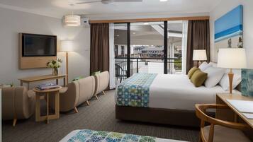 A hotel room with a bed, a desk, a TV, a chair, and a balcony with a view.