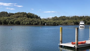 A calm lake with a dock, a white boat, and a forested shore.