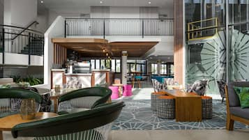 A spacious lobby with a high ceiling, a staircase, and a seating area with modern furniture.