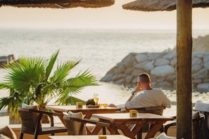 A man sitting at a wooden table with a view of the sea.