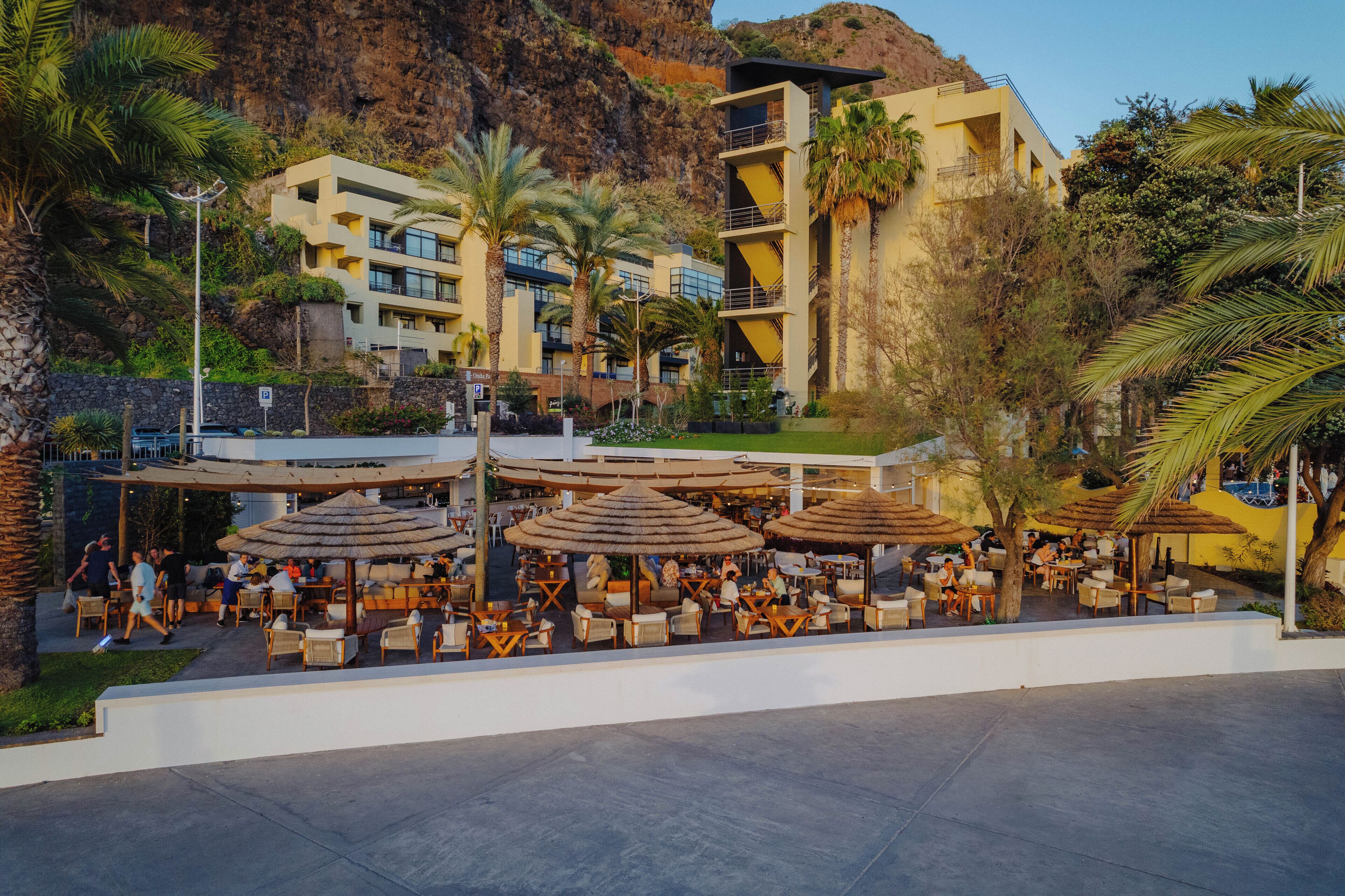 Un complexe hôtelier doté d’une terrasse, de palmiers et offrant une vue sur les montagnes.