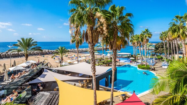 A resort with a pool, palm trees, and a beach area.
