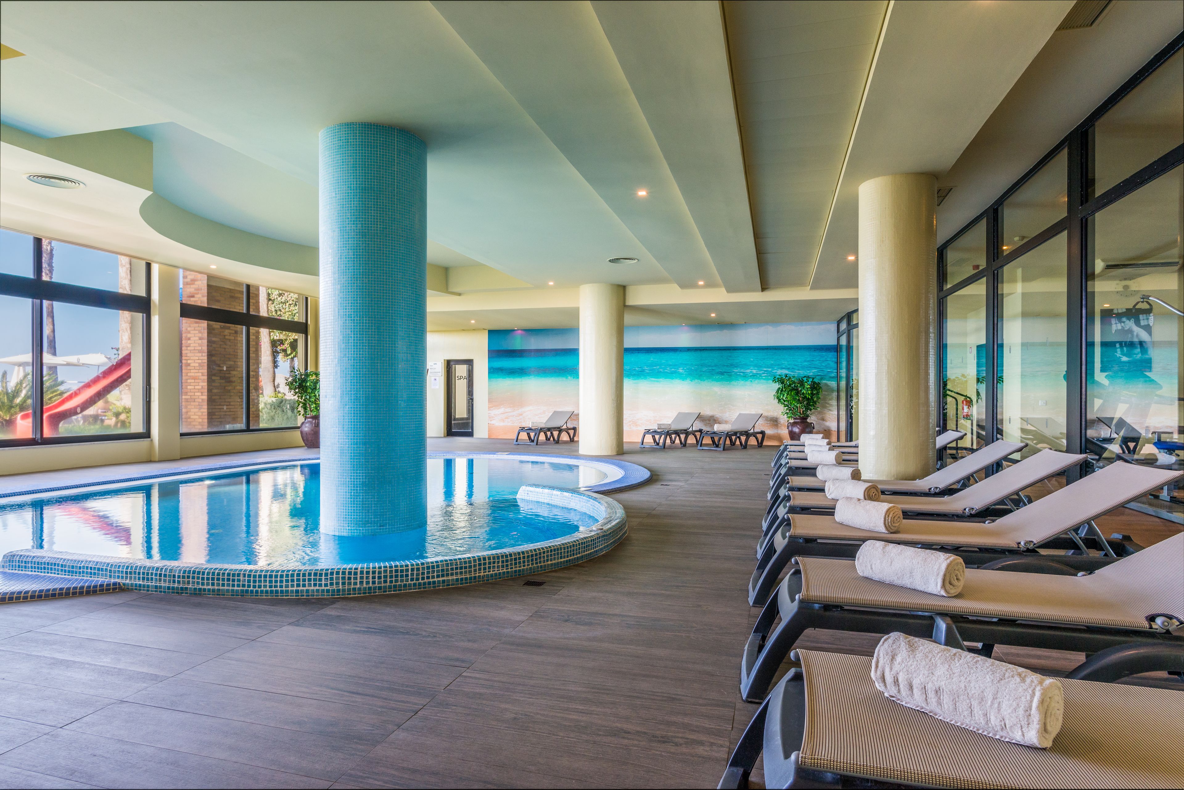 Una piscina interior amb gandules i vistes a l'oceà a través de grans finestres.