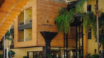 A multi-story hotel with a brick facade and a sign reading "Calheta Beach".