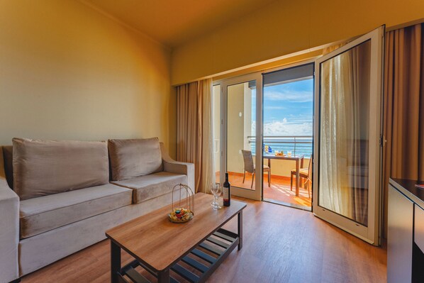A modern living room with a sofa, a coffee table, and a view of the ocean through large sliding glass doors.